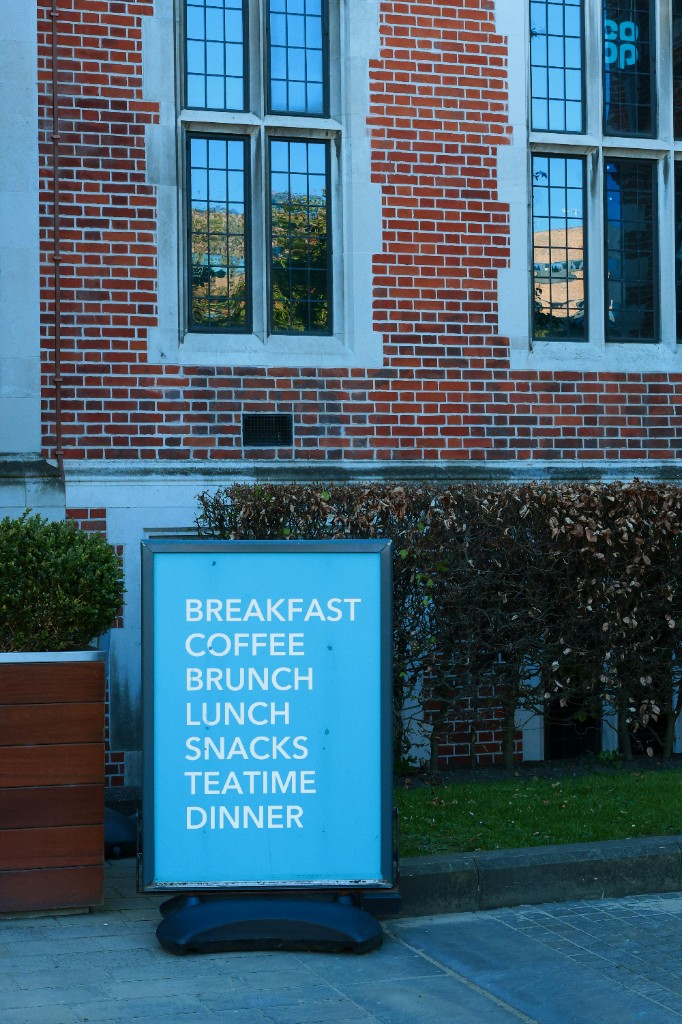 Outdoor pavement sign with menu graphics outside a brick building